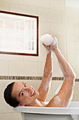 Caucasian woman taking bubble bath in bathroom