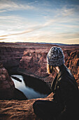 Young Woman Sitting at Edge of Horseshoe Bend at Sunset, Arizona, USA