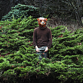 Man wearing bear mask while standing amidst plants