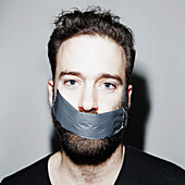 Portrait of man with adhesive tape covering his mouth