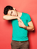 Tired young man sleeping on hand against red background