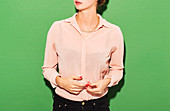 Midsection of woman in smart casuals standing against green background