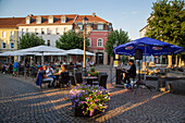 Pianist performs live music as patrons sit outside restaurants on Marktplatz market square in Altstadt old town