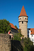 Young couple sits on wall near tower of Kirchenburg fortified church in Altstadt old town
