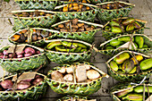 a selection of tropical vegetables is offered in baskets made from palm fonds at the Port Vila markets.