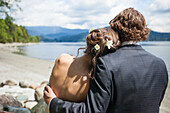 A young attractive couple embrace each other while at the looking out at Burrard Intlet, Vancouver B.C.