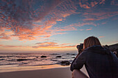 Girl (20-30 years old)  taking photo of the sunset from the beach, very near to the shore. Fuerteventura, Canary Islands