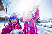 Young girls smiling and playing in the snow on a beautiful winter day.