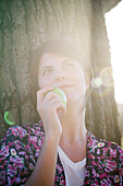 Woman holding apple, looking up dreamily, portrait