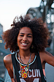 Young afro-american woman smiling on a steel bridge in urban scenery, Hackerbruecke bridge, Munich, Bavaria, Germany