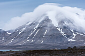 Wolken ziehen über einen Gipfel hinter Häusern des Orts Ny-Ålesund auf der Südseite des Kongsfjords, Spitzbergen, Svalbard Archipel, Norwegen