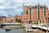 A launch on harbour cruise passes the Busanbrücke on the IMMH international maritime museum of Hamburg, in the background the (112-m-high) city hall tower, harbour city, Hamburg, Germany