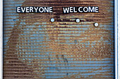 'Eine verwitterte Hinweistafel mit dem Schriftzug ''Jeder Willkommen'' aus einzelnen Buchstaben aus Metall, Toronto, Kanada '