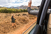 A tourist films and waves to a local Zimbabwean child