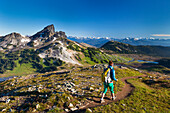 A young woman backpacking on the Panorama Ridge Trail with Black Tusk Mountain in the background in Garibaldi Provincial Park, British Columbia, Canada.