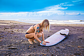 Young woman with surfboard on a beach.