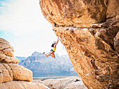 Mixed race girl rock climbing on cliff