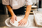 Chef shaping pizza dough in restaurant kitchen