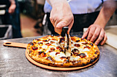 Chef slicing pizza in restaurant kitchen