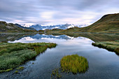 The mountain range is reflected in Fenetre Lakes at dusk, Ferret Valley, Saint Rhemy, Grand St Bernard, Aosta Valley, Italy, Europe
