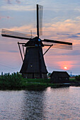 Blue sky and pink clouds on the windmill reflected in the canal at dawn, Kinderdijk, Rotterdam, South Holland, Netherlands, Europe