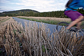 Young woman riding with her bike on a way between fields