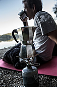 Junger Camper trinkt Kaffee an einem See, Freilassing, Bayern, Deutschland