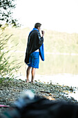 Young male camper brushing his teeth at a lake, Freilassing, Bavaria, Germany