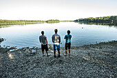 Three young men standing at a lake, Freilassing, Bavaria, Germany