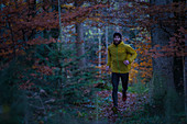 Junger Mann läuft auf einem Weg durch einen Wald, Allgäu, Bayern, Deutschland