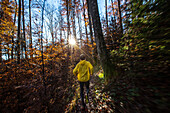 Young man running on a trail through a forest, Allgaeu, Bavaria, Germany