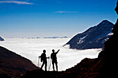 Two trekkers hike above the clouds, Engadina, Swiss alps, Switzerland