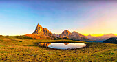 Gusela mountain at sunrise reflected in small lake, Giau Pass, Dolomites, Veneto, Italy.
