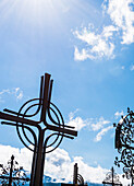 Ein typisches Metallkreuz auf einem Friedhof vor blauem Himmel, Aldein, Südtirol, Alto Adige , Italien