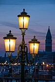 Lit lamposts on San Marco basin, and campanile, San Marco, Venice, Italy.