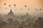 Balloons fly over the temples of Bagan, Myanmar at sunrise.
