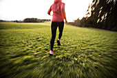 Young woman running over a field, Allgaeu, Bavaria, Germany