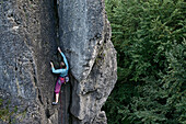 Young woman climbing at a rock face, Pottenstein, Franconia, Germany