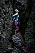 Junge Kletterin steht zwischen Felsen und sieht nach oben, Pottenstein, Franken, Deutschland
