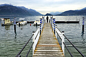 Lake Como, single man on the platform in Menaggio looking in Bellagio direktion, Varenna on left in background, Como province, Lombardy, Italy.