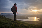 Female hiker takes in view of Llangorse lake from Mynydd Llangorse, Brecon Beacons national park, Wales.