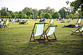 People sitting on deck chairs, Hyde Park, London, UK.