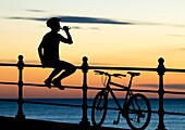 Mountain biker watching the sun rise at Seaton Carew on the North east coast of England. United Kingdom.