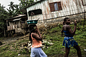Zwei einheimische Mädchen gehen an einem einfachen Haus vorbei, Sao Tome, Sao Tome und Príncipe, Afrika