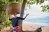 Young woman trying to carry a big basket on her head, Sao Tome, Sao Tome and Principe, Africa
