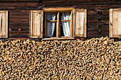 Holzhaus, Fenster, Vorhänge, gestapeltes Brennholz, Energie, Heizen, Vorrat für den Winter, Bregenzerwald, Vorarlberg, Österreich