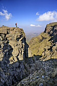 Woman hiking looking down to deep gorge, Rhino Peak in background, Rhino Peak, Garden Castle, Mzimkhulu Wilderness Area, Drakensberg, uKhahlamba-Drakensberg Park, UNESCO World Heritage Site Maloti-Drakensberg-Park, KwaZulu-Natal, South Africa