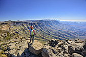 Frau beim Wandern steht am Giant's Castle und blickt auf Longwall und Little Berg, vom Giant's Castle, Drakensberge, uKhahlamba-Drakensberg Park, UNESCO Welterbe Maloti-Drakensberg-Park, KwaZulu-Natal, Südafrika