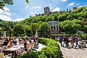 Ein gut besuchtes Straßenrestaurant mit Blick auf die Alhambra, Granada, Andalusien, Spanien