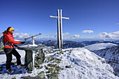 Frau steht am Gipfel des Falkert und schaut auf Panoramaanzeiger, Falkert, Nockberge, Biosphärenpark Nockberge, Kärnten, Österreich